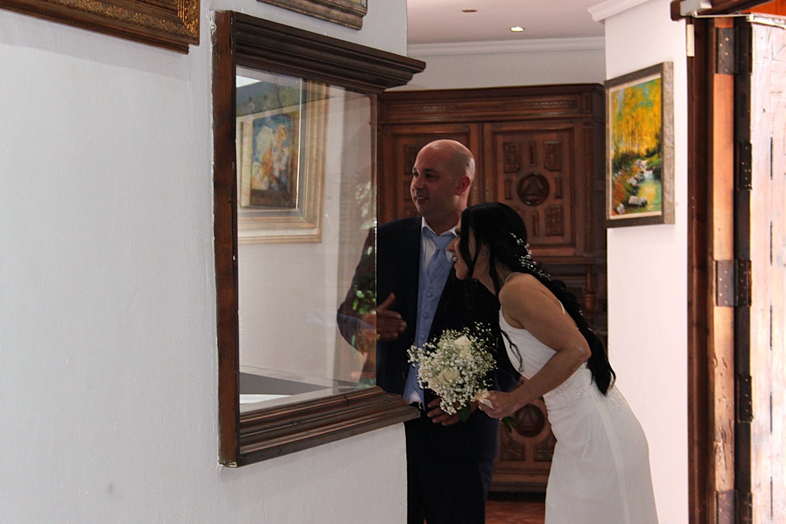 Los novios se miran en el espejo de la entrada